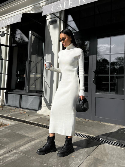 Woman in a white dress standing outside a cafe holding a coffee cup.