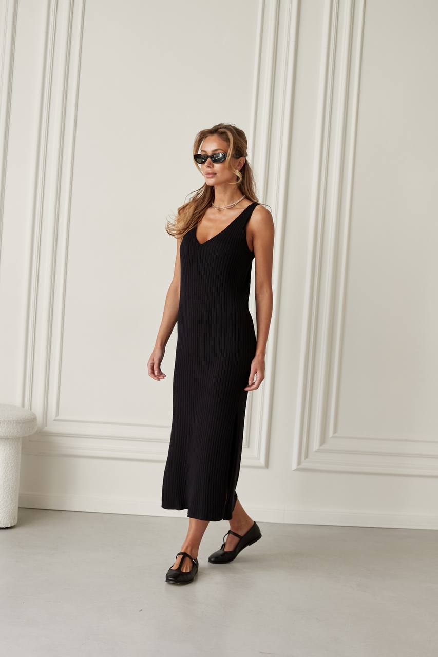 Woman wearing a black sleeveless dress against a white wall