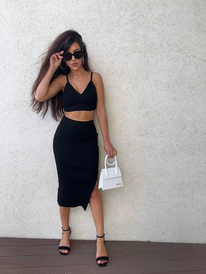 Woman in black outfit holding a white handbag against a light background