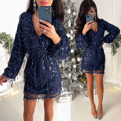 Woman wearing a navy blue sequin dress in front of a decorated Christmas tree.