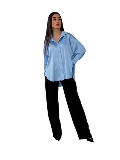 Woman wearing a light blue shirt and black pants on a white background