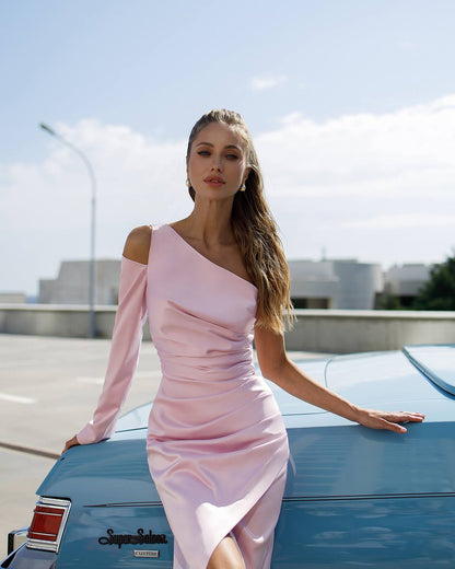 Woman in a pink dress leaning on a blue car with a clear sky background