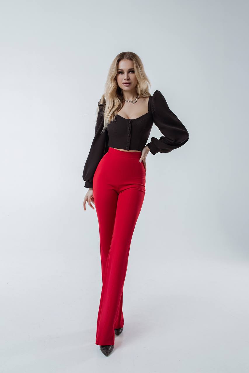 Woman wearing a black top and red pants on a white background