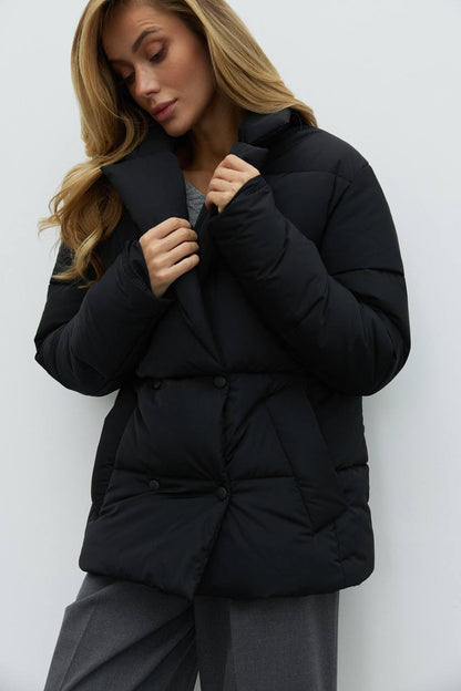 Woman wearing a black puffer jacket against a white background