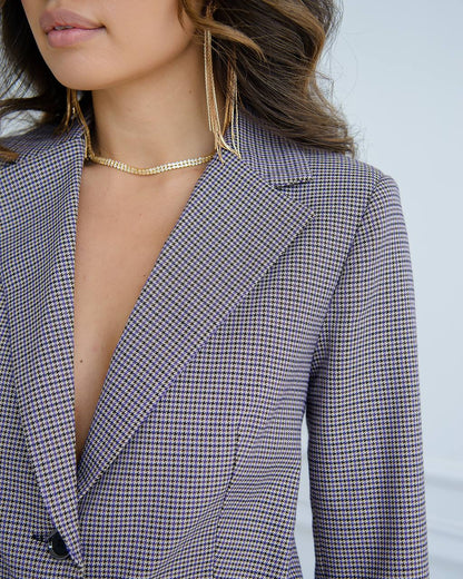 Person wearing a houndstooth pattern blazer with a blurred background