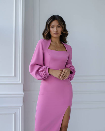 Woman wearing a pink dress with a slit, standing against a white wall.
