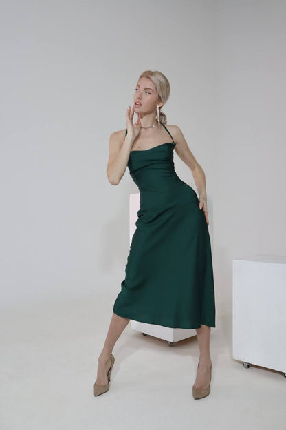 Woman wearing a green dress standing against a plain background