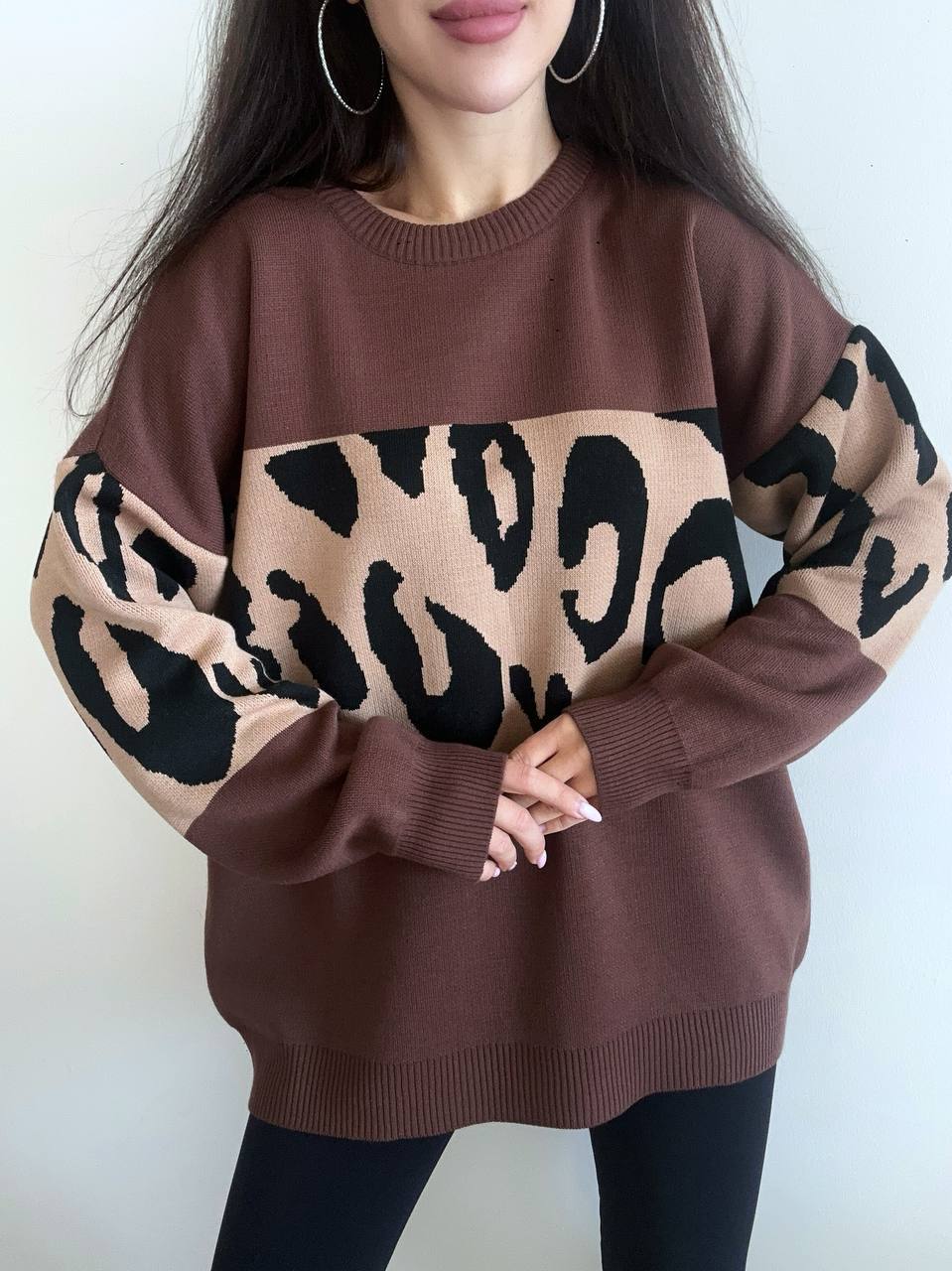 Brown sweater with leopard print sleeves worn by a person on a white background