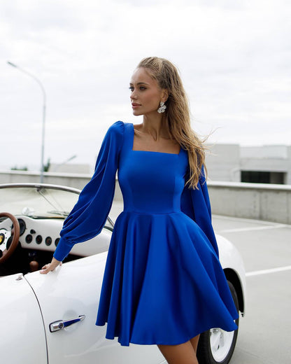 Woman in a blue dress standing next to a white car on a rooftop.
