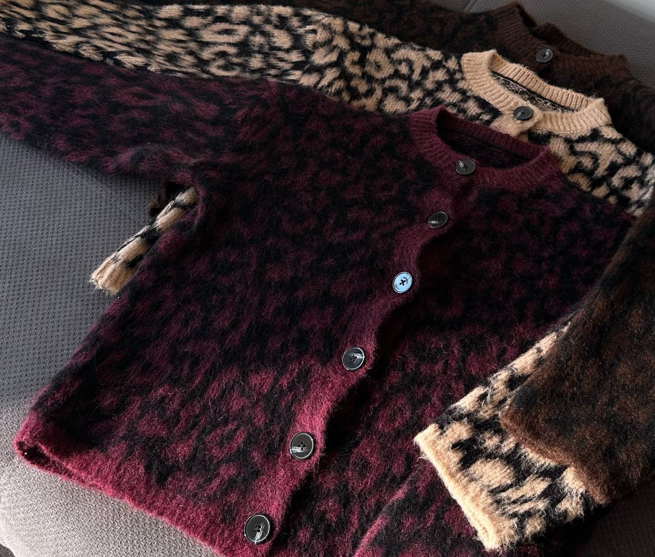 Patterned cardigans including leopard print and brown colors on a gray surface.