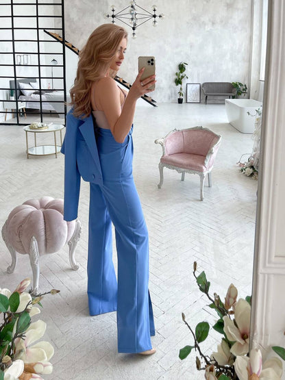 Woman in a blue outfit taking a mirror selfie in a stylish room with decor elements.