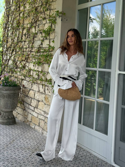 Woman in white outfit standing in front of a stone building with a door.
