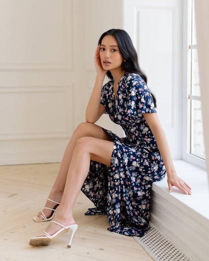 Woman in a floral dress sitting by a window in a bright room