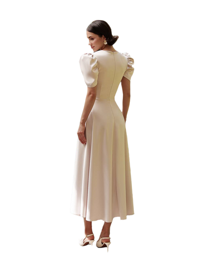 Woman wearing a beige dress with ruffled sleeves on a white background