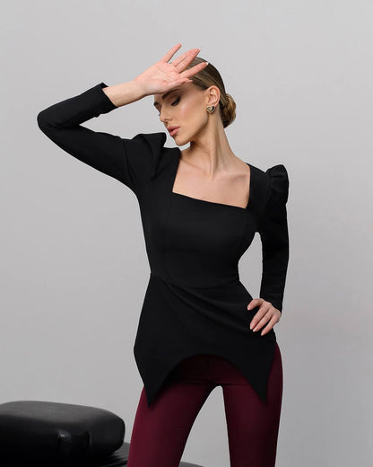 Woman wearing a black long-sleeve top with a unique cutout design on a gray background