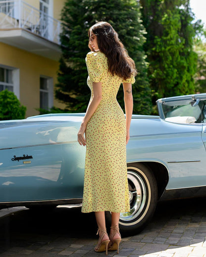 Woman in a yellow dress standing next to a vintage car