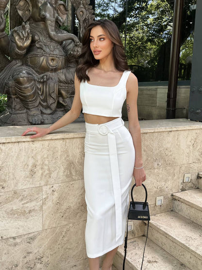 Woman in a white outfit standing in front of a stone sculpture