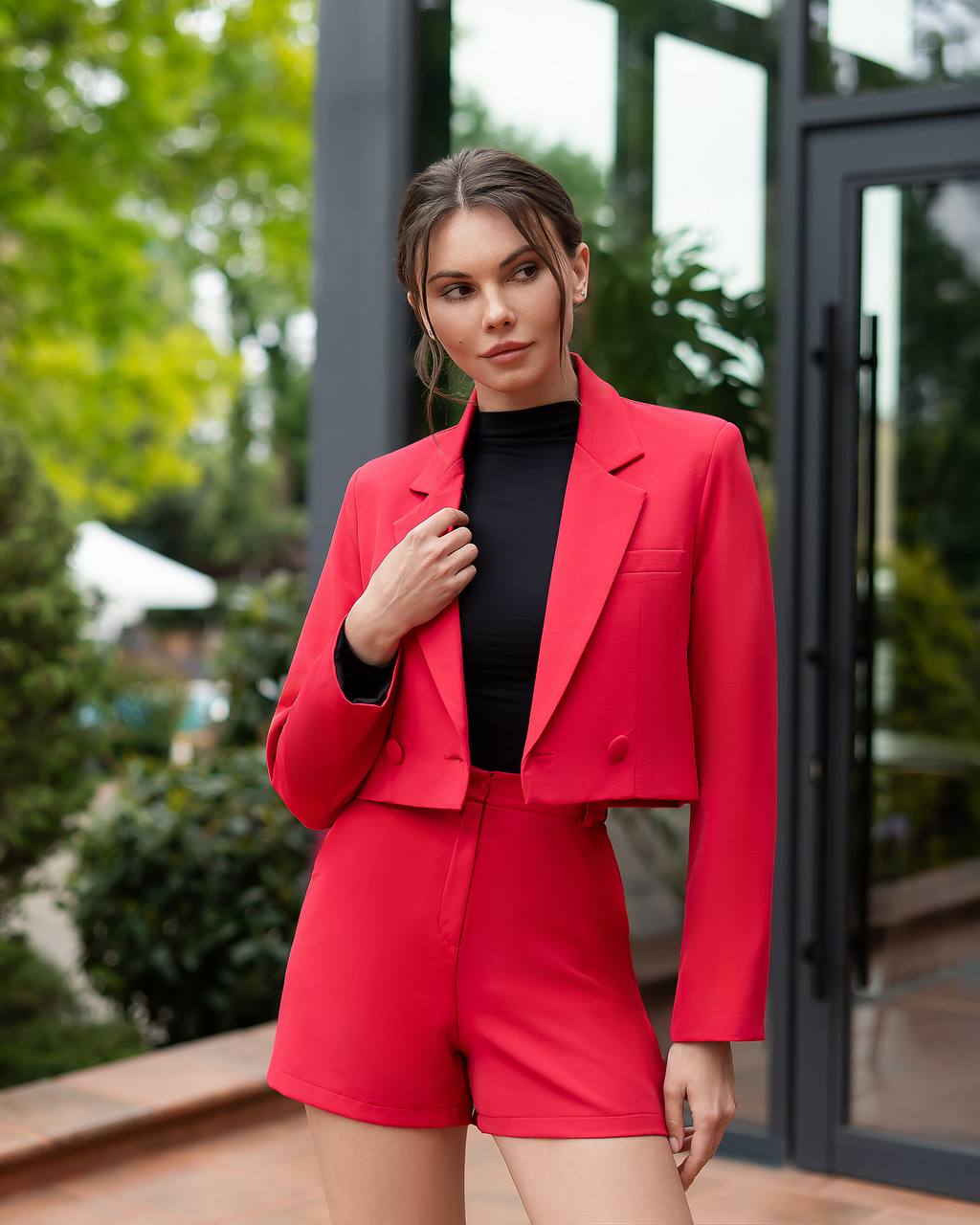 Woman wearing a red blazer and shorts set outdoors.