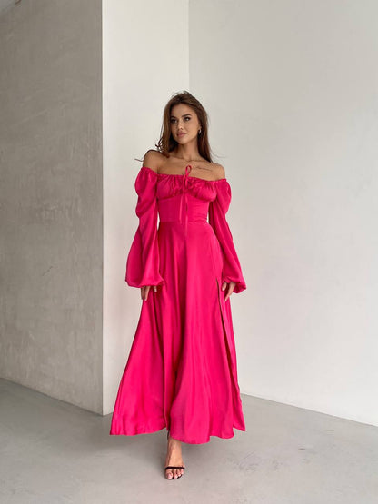 Woman wearing a bright pink off-shoulder dress against a plain background