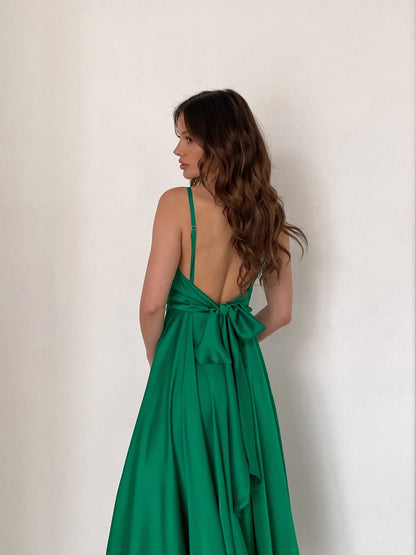 Woman wearing a green dress with a bow detail on a plain background