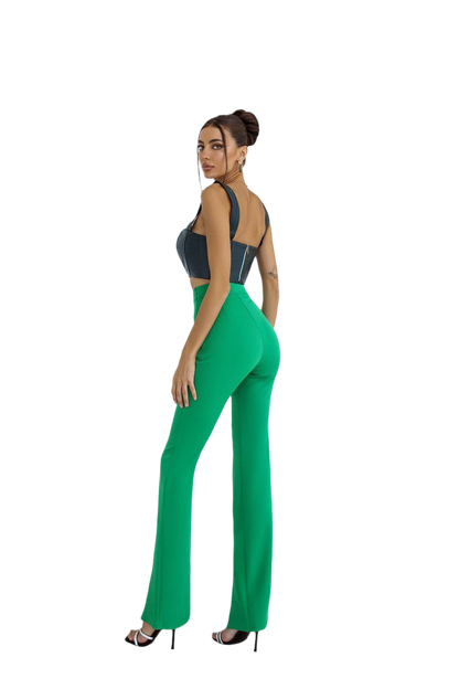 Woman wearing a black top and green pants on a white background