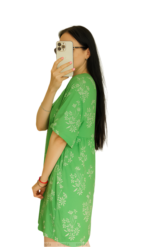 Woman wearing a green floral dress against a white background