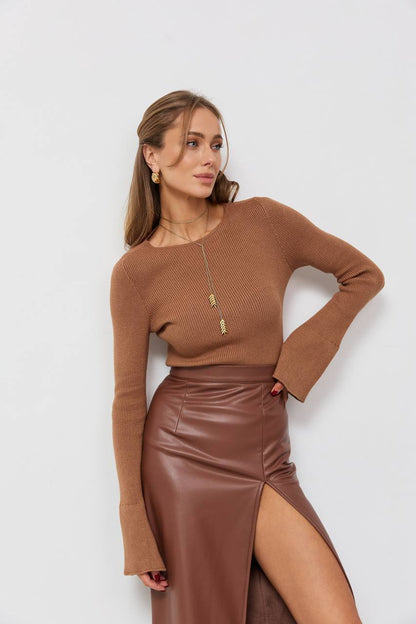 Woman wearing a brown sweater and leather skirt against a white background