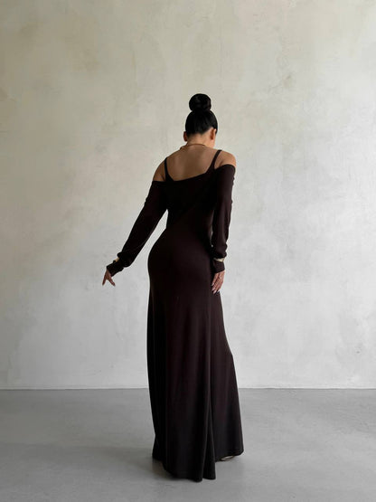 Woman wearing a long black dress with off-shoulder sleeves against a plain background