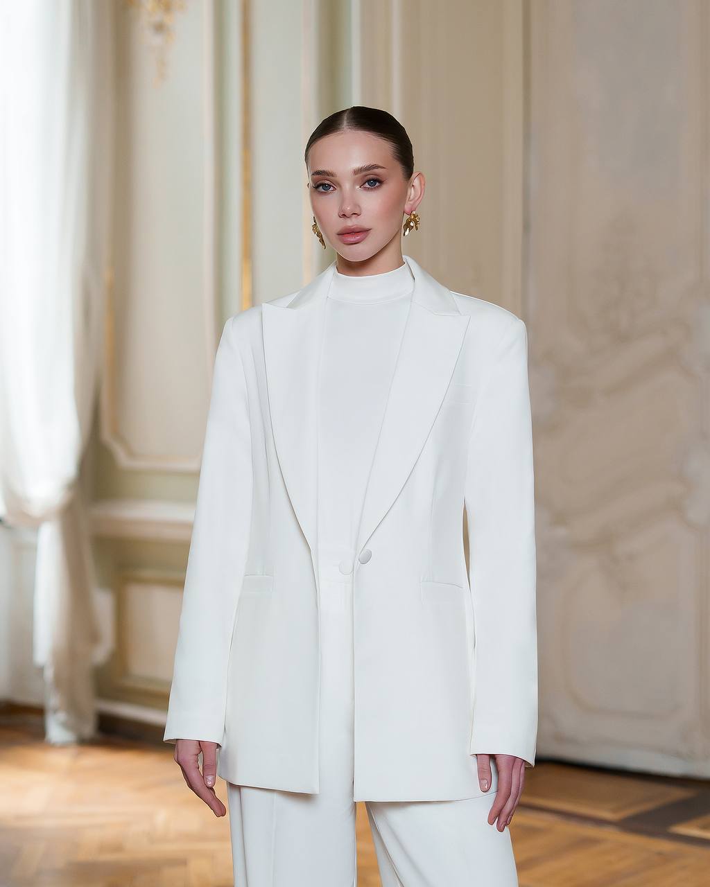 Woman wearing a white suit in an elegant indoor setting
