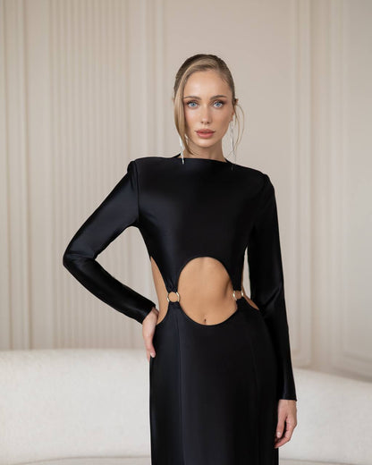 Woman wearing a black dress with cut-out design against a neutral background