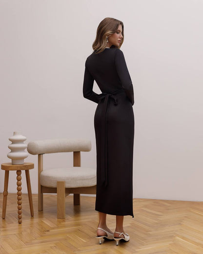 Woman in a black dress standing in a room with wooden floor and white walls