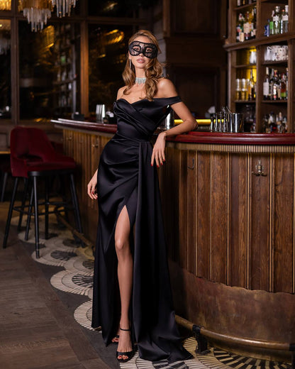 Woman in a black evening gown and mask standing in a bar setting