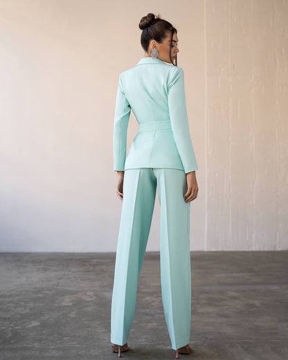 Woman wearing a light blue suit standing against a neutral background