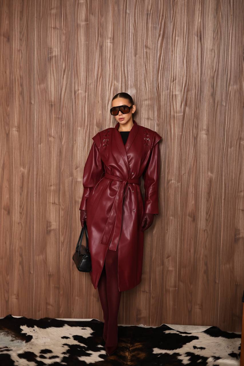 Person wearing a burgundy leather coat against a wooden wall.