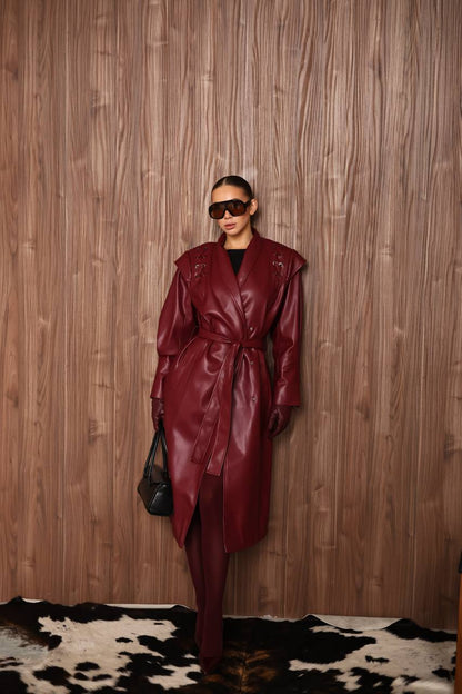 Person wearing a burgundy leather coat against a wooden wall.