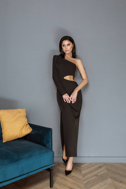 Woman in a black one-shoulder dress standing against a gray wall with a blue couch and yellow pillow.