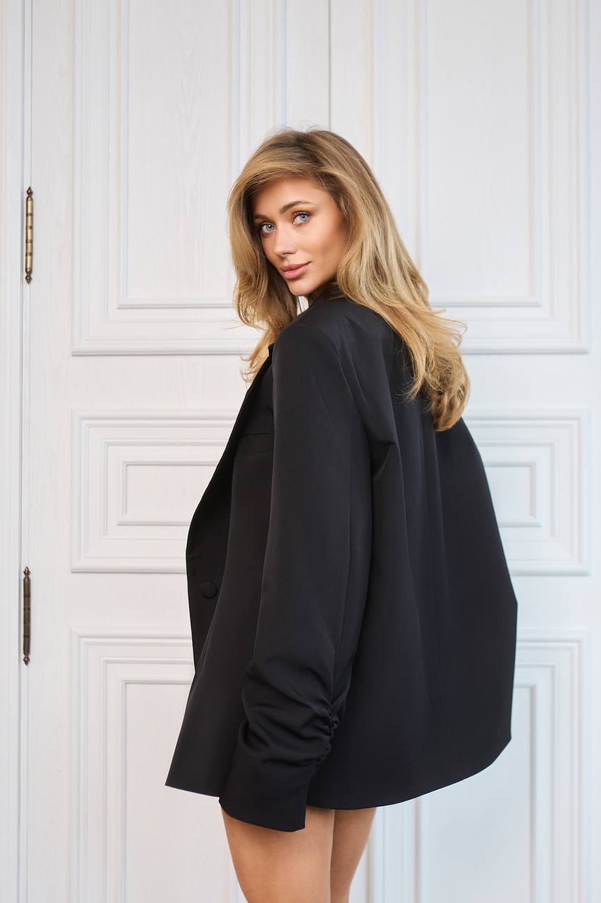 Woman wearing a black blazer against a white paneled wall