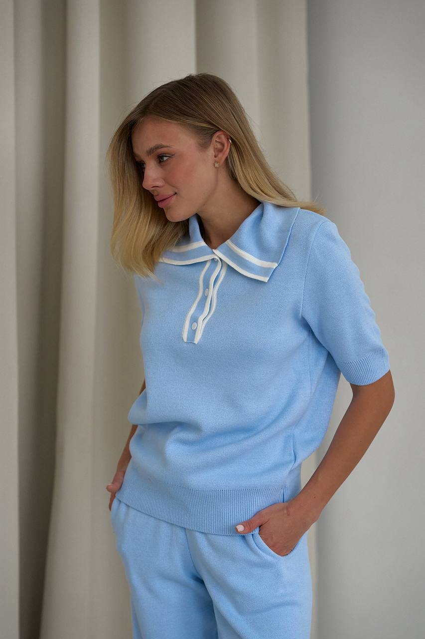 Woman wearing a light blue outfit with a white collar against a neutral background