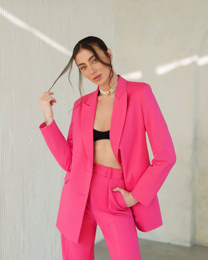 Woman wearing a bright pink suit with a black top against a neutral background