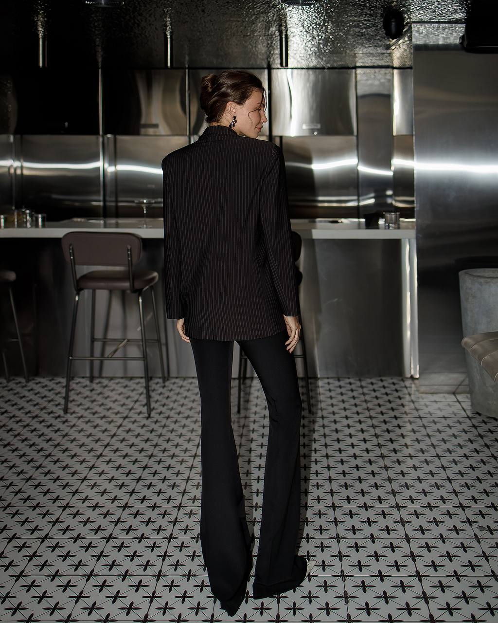 Person wearing a black pinstripe suit in a modern kitchen setting