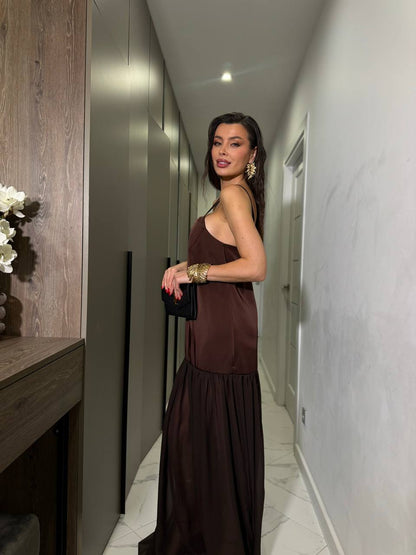 Woman in a brown dress standing in a modern hallway.