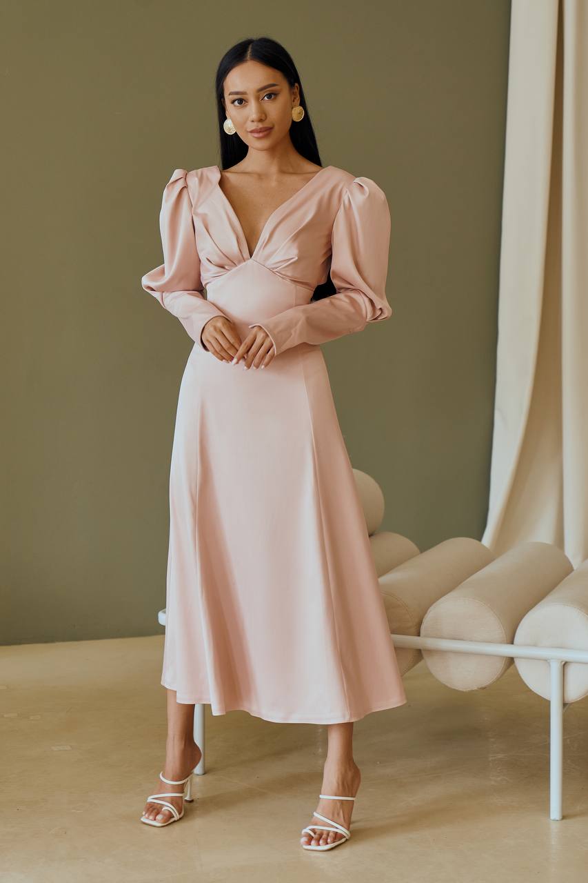 Woman wearing a pink dress standing in a room with a neutral color palette.