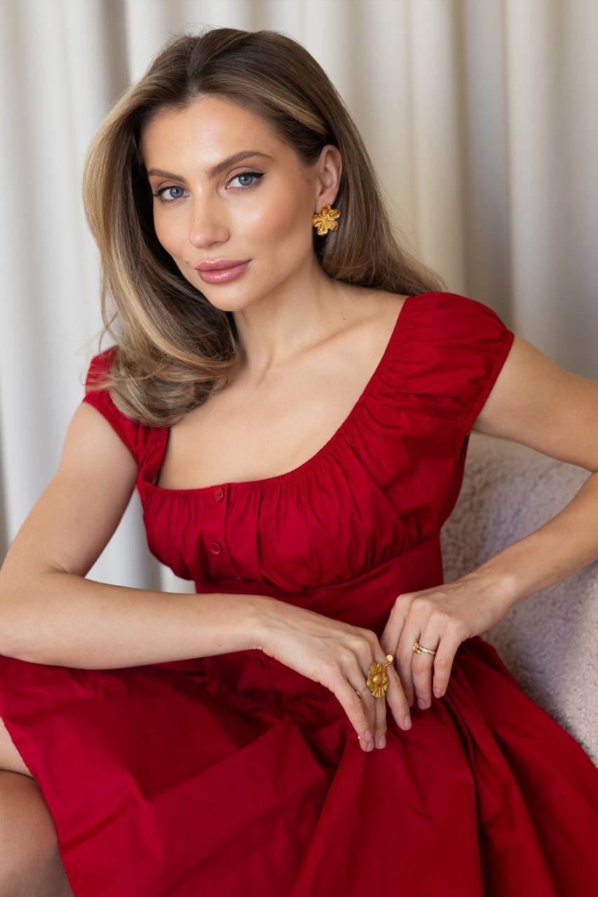 Woman in a red dress sitting against a neutral background