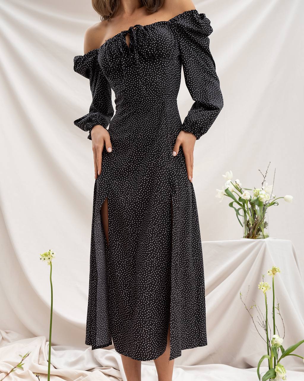 Black polka dot off-shoulder dress with long sleeves on a white background