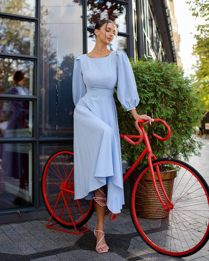 Woman in a light blue dress standing next to a red bicycle outdoors.