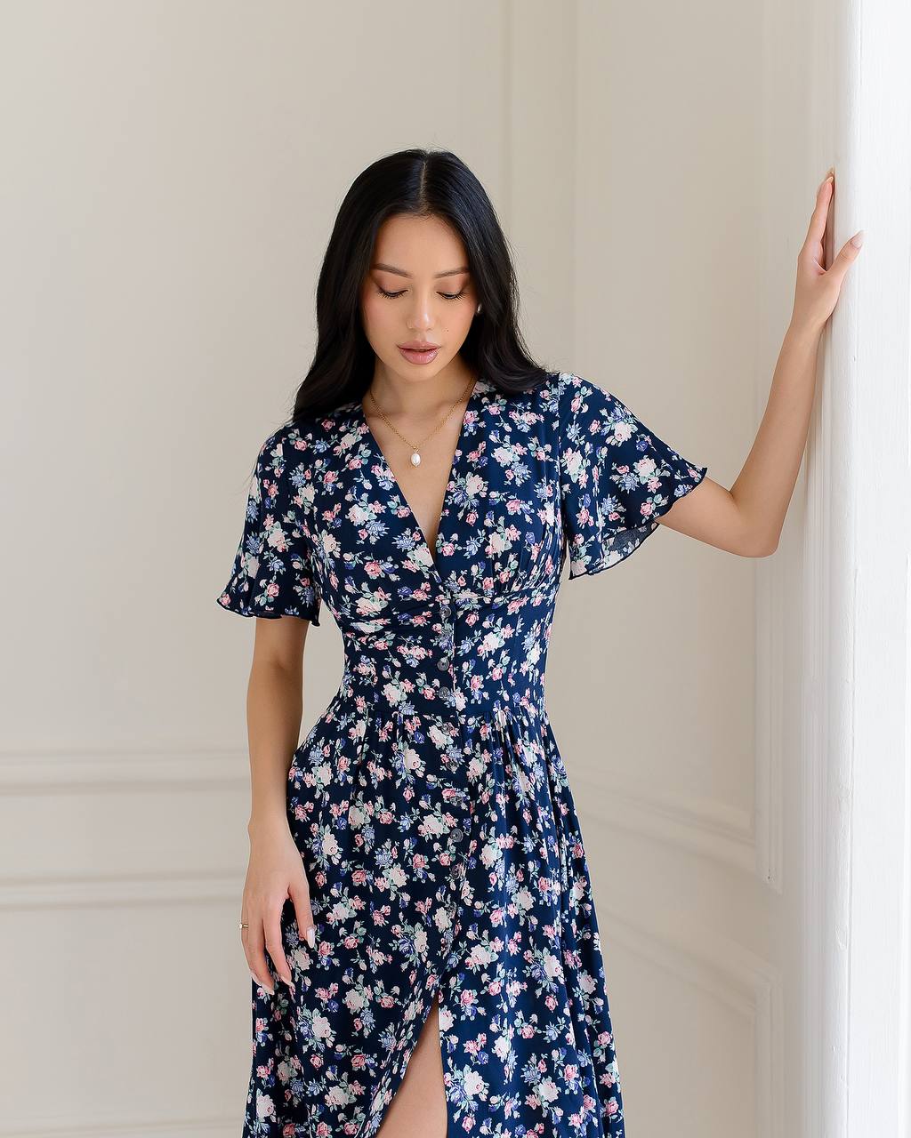 Woman wearing a navy floral dress against a neutral background