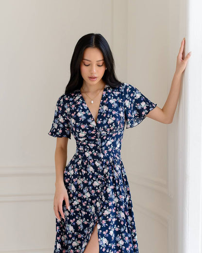 Woman wearing a navy floral dress against a neutral background