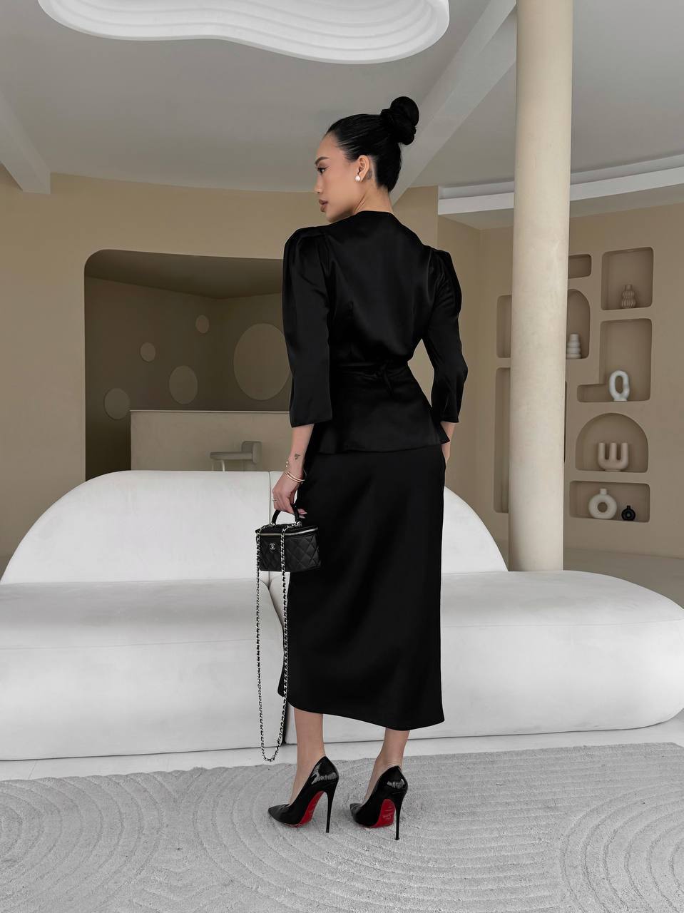 Woman in a black outfit standing in a modern interior setting