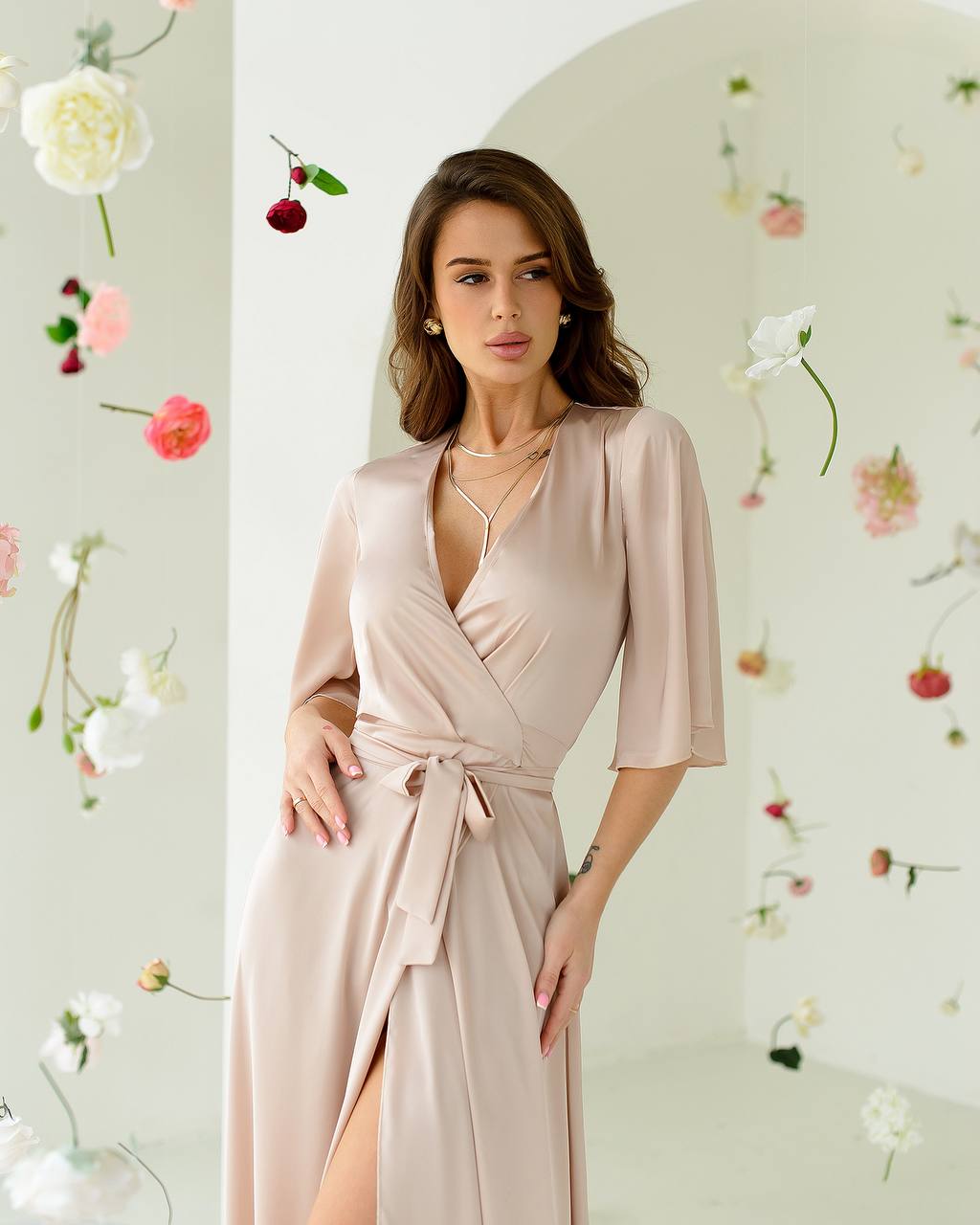 Woman wearing a beige wrap dress with a floral background