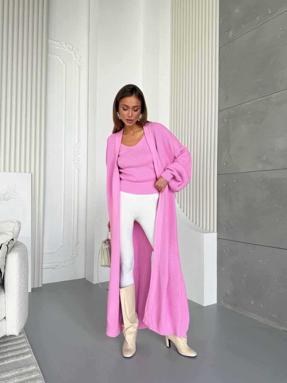 Woman in a pink outfit standing in a room with white walls and gray floor.